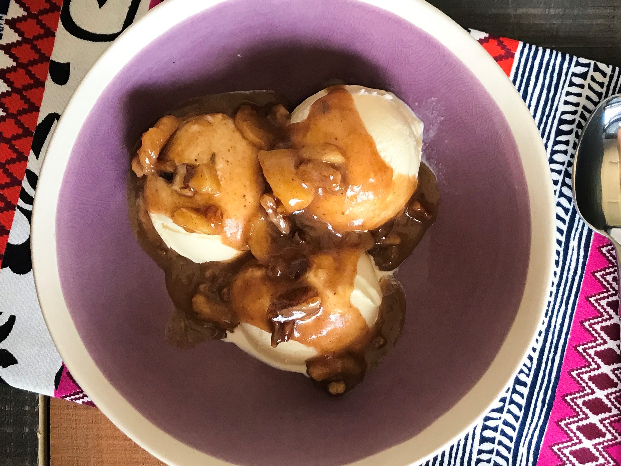a bowl of banana bliss with 3 scoops of ice cream topped with a glaze