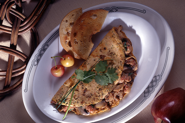 a plate of crawfish mushroom omlet with 2 pieces of bread as a side and 2 cherries