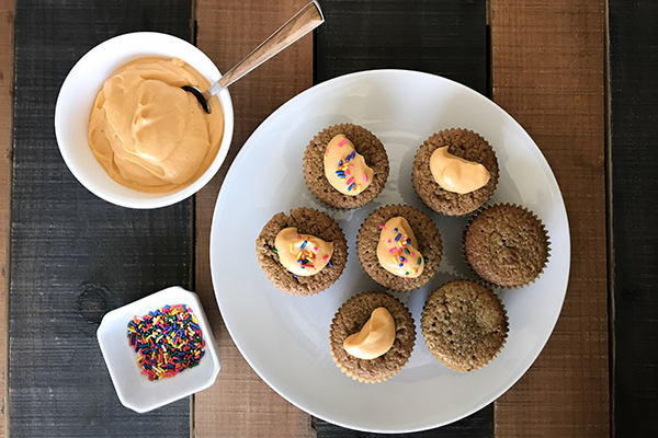 7 cupcakes on a plate with papaya sauce frosting on top and sprinkles