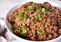 a bowl of dirty rice with green onions on top