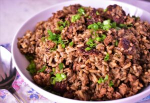 a bowl of dirty rice with green onions on top