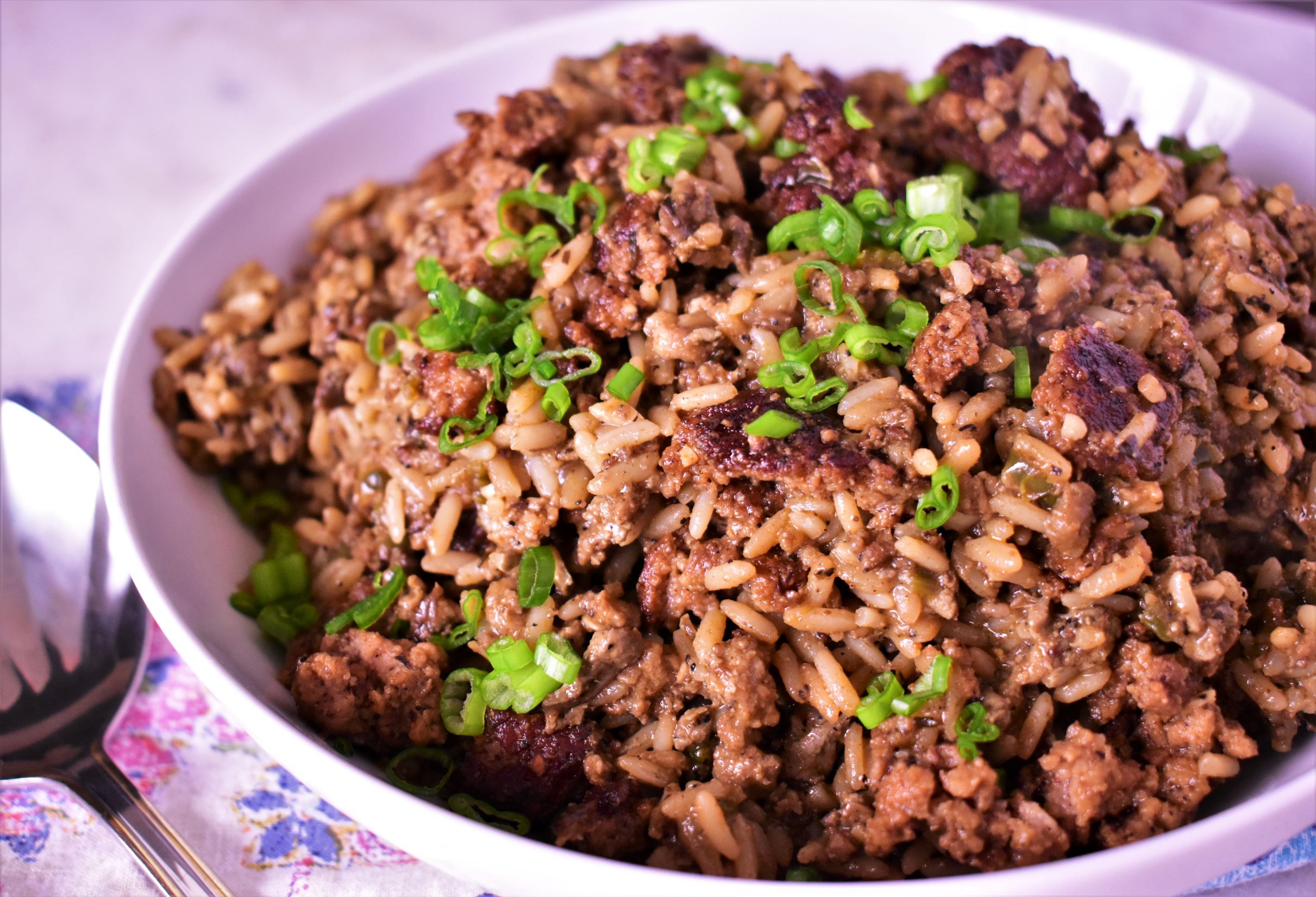 a bowl of dirty rice with green onions on top