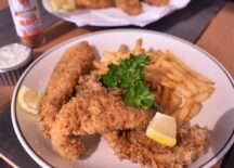 a plate of friday fish fry fish with seasoned fries and 2 lemon slices for garnish