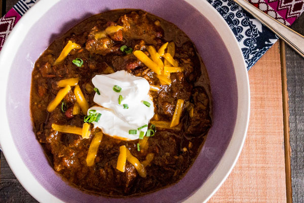 a bowl of glenn's magic Chili with shredded cheese and a dollap of whipped cream