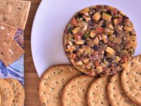 a plate of grilled vegetable tartar next to a bunch of circular and square crackers