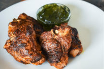 a plate of bronze Lamb Chops with a cup for dipping