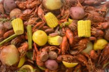 a close up of a crawfish boil with corn, potatoes and sausage