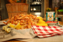 a side view of a table full of louisiana shrimp boil with a lot of shrimp and a few corn cobs and lemon slices