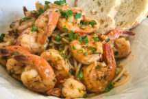 a plate full of magic shrimp scampi and a side of 2 pieces of bread