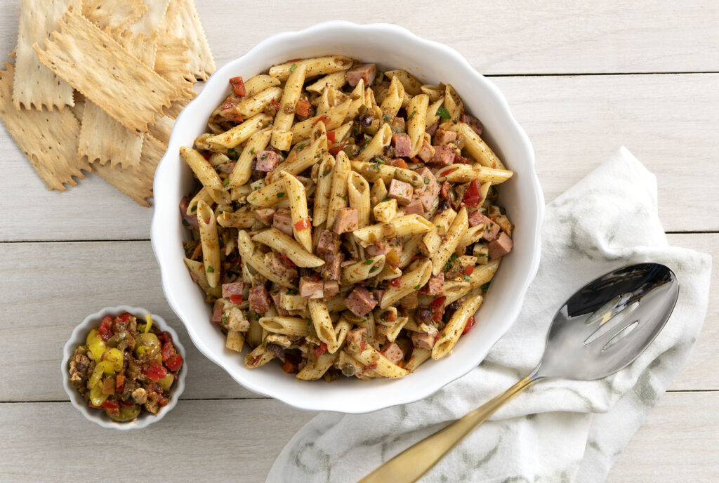 a bowl of muffuletta pasta salad next to a side of crackers