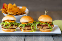 3 sweet basil and tarragon turkey sliders cooked with salt free sugar free magic seasoning blends with a cup of chips in the background