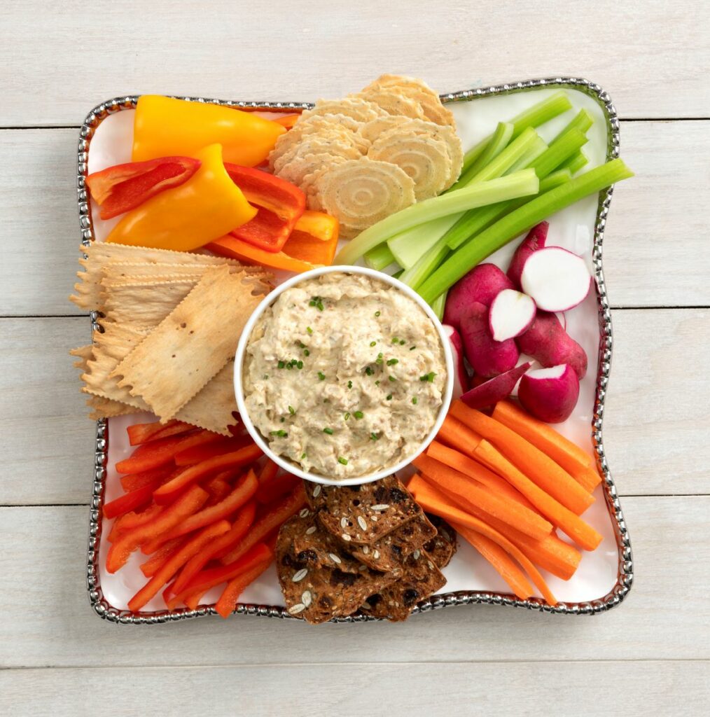 a bowl of chilled shrimp dip surrounded by a plate of various food items to dip into it