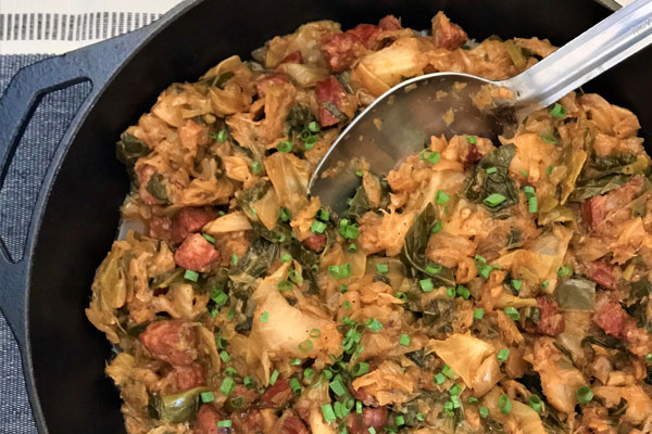 a cast iron pot full of smothered cabbage and greens