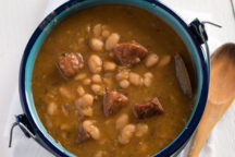 a dutch oven full of white beans with andouille sausage