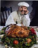 chaf paul sitting next to agolden roasted turkey on a table