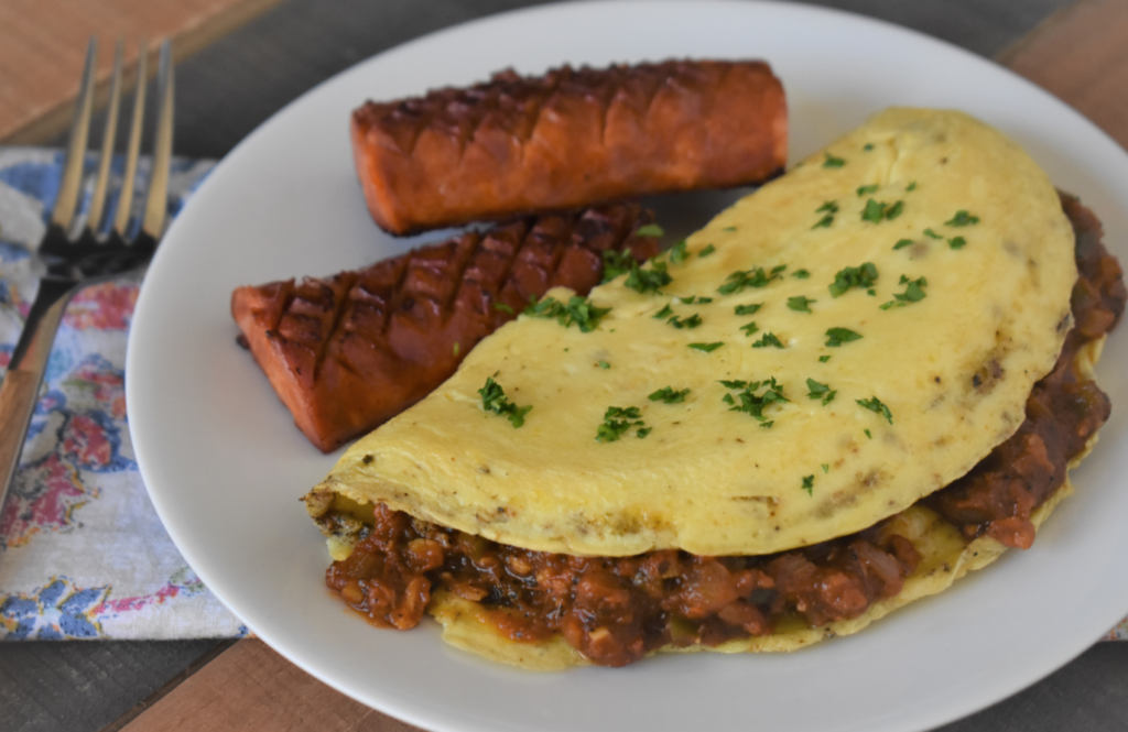 a plate with an eye opener omlet and 2 links of sausage