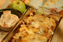 a dish of new mexico apple bread pudding next to a granny smith apple and a bowl of ice cream