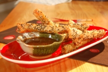 a close up of a plate of pick up sticks with a cup full of dipping sauce