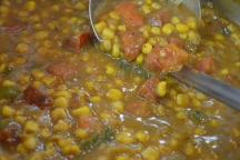 a close up of corn and andouille soup in a pot with a ladle in it, cooked with salt free sugar free magic