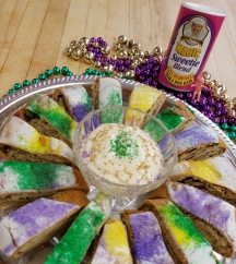 pieces of king cake surrounding a cup of mardi gras magic dippin sauce