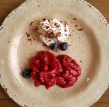 a plate with 2 love potion pralines on it and a side of whipped cream and blueberries