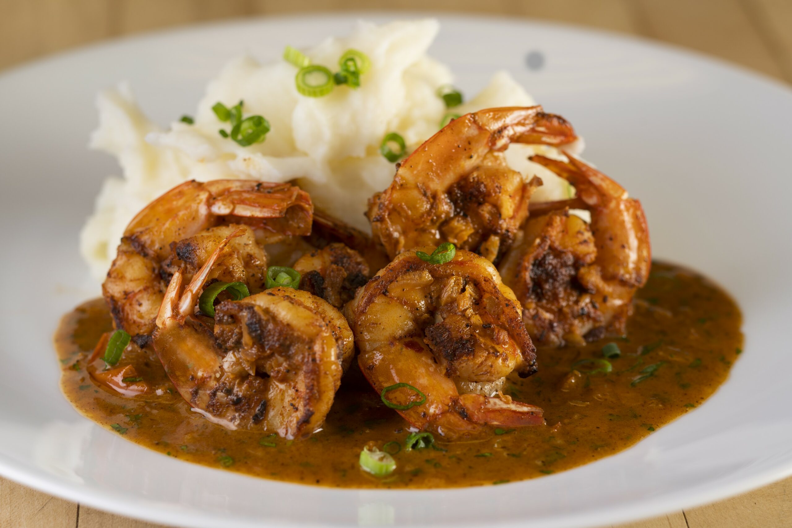 a close up of a plate of chipotle lemon shrimp and a side of mashed potatoes and green onions