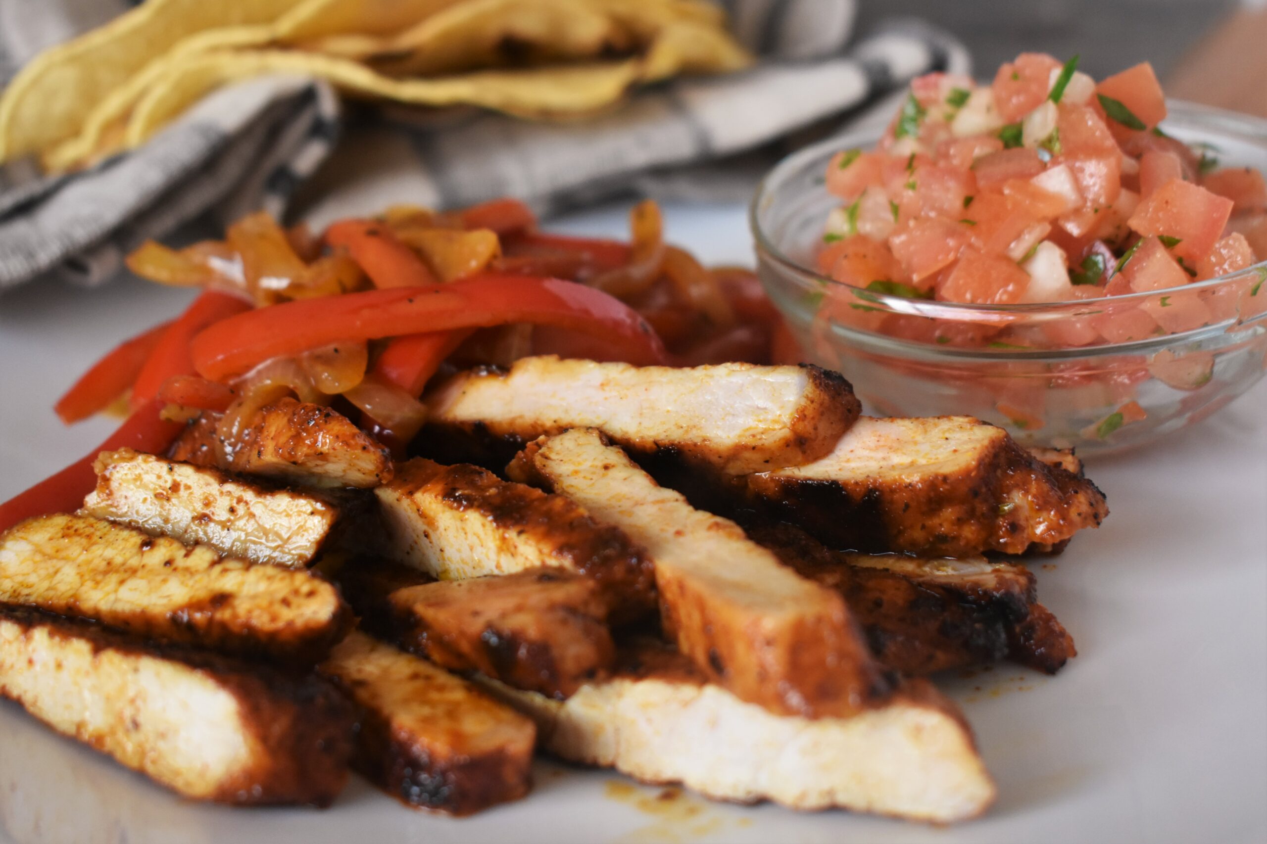 a plate of fajita style chipotle pork chops next to a side cup of pico de gallio