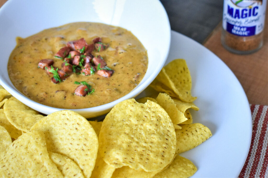 a bowl of jambalaya queso surrounded by chips on a plate