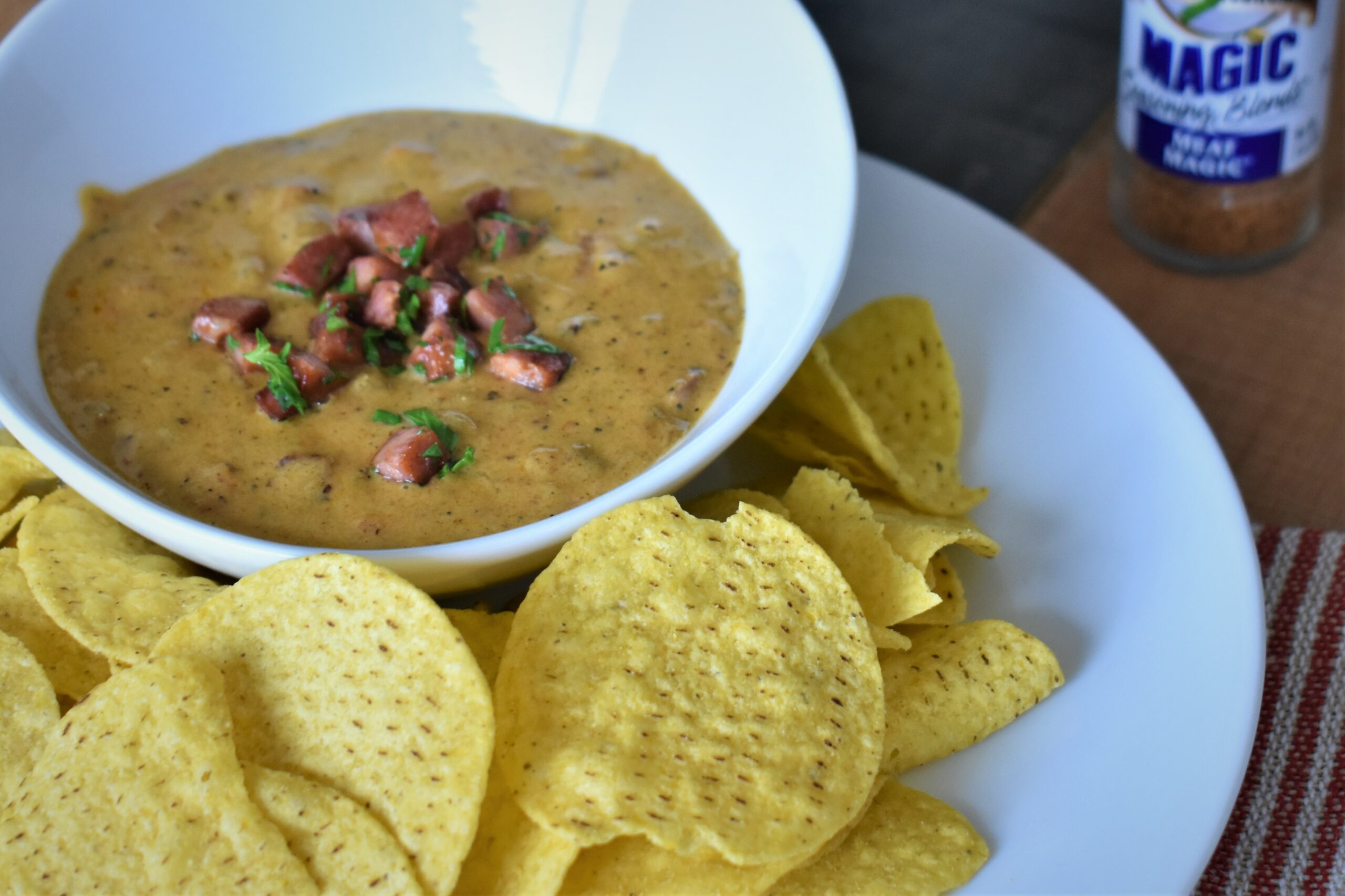 a bowl of jambalaya queso surrounded by chips on a plate