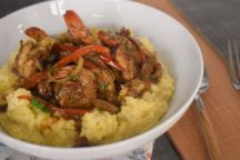 a bowl of jerk bbq shrimp on top of mashed potatoes
