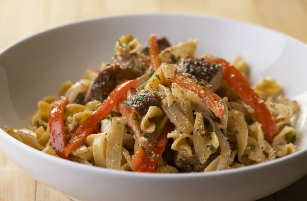 a close up of a bowl of jerk chicken pasta