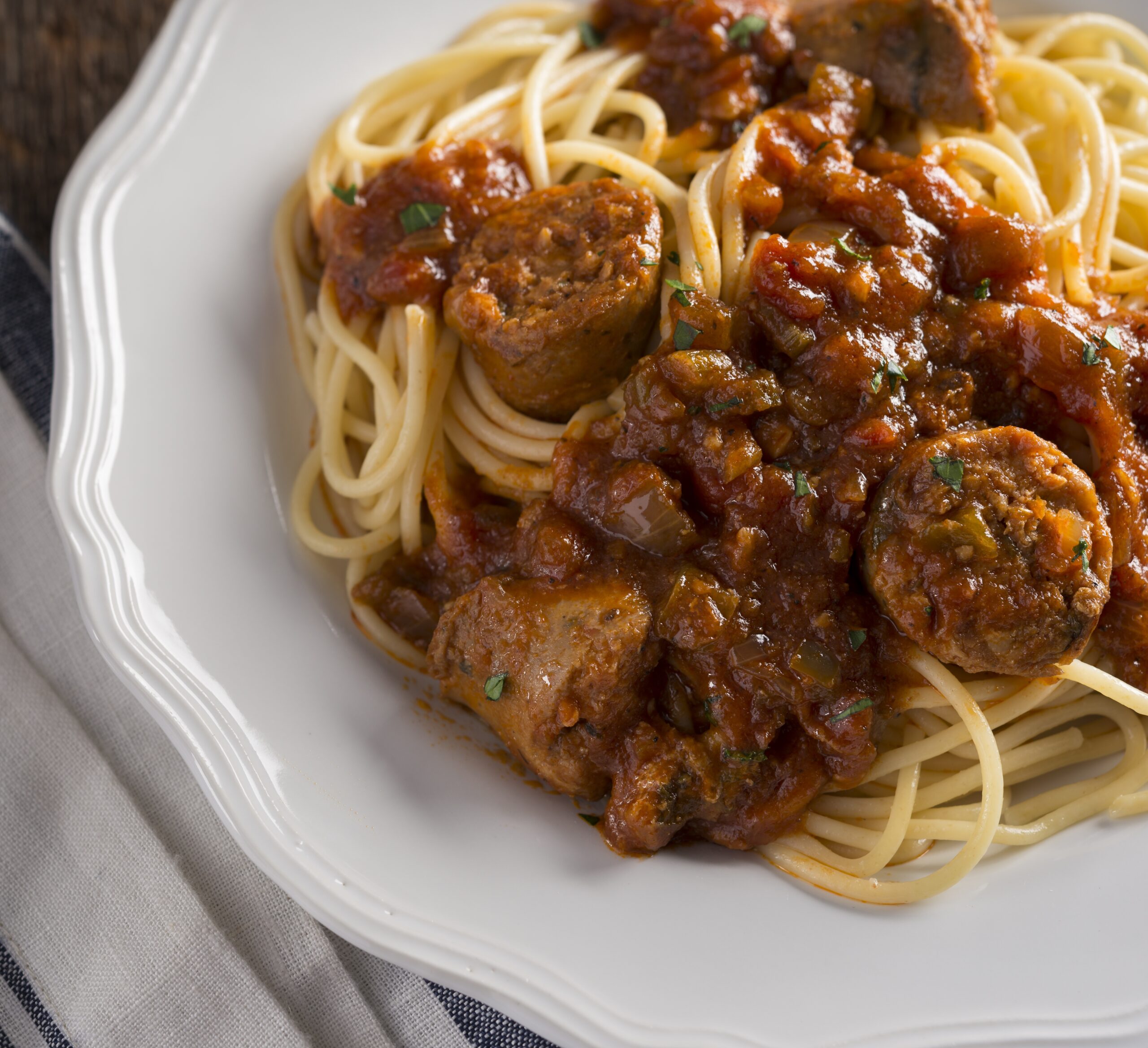 a plate of cajun sausage in red gravy with noodles