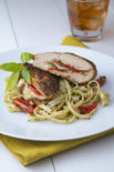 a plate of caprese chicken breasts on top of noodles