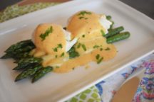 a plate with creole hollandaise sauce on top of cooked asparagus