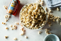 a bowl of salmon magic topped popcorn next to a container of salmon magic with popcorn on the table