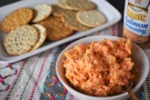 a bowl of pimiento cheese next to a plate of crackers