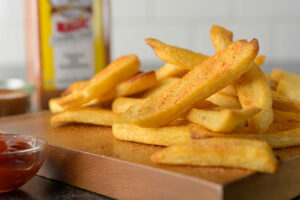 a cutting board full of french fries with seasoning freshly poured on it