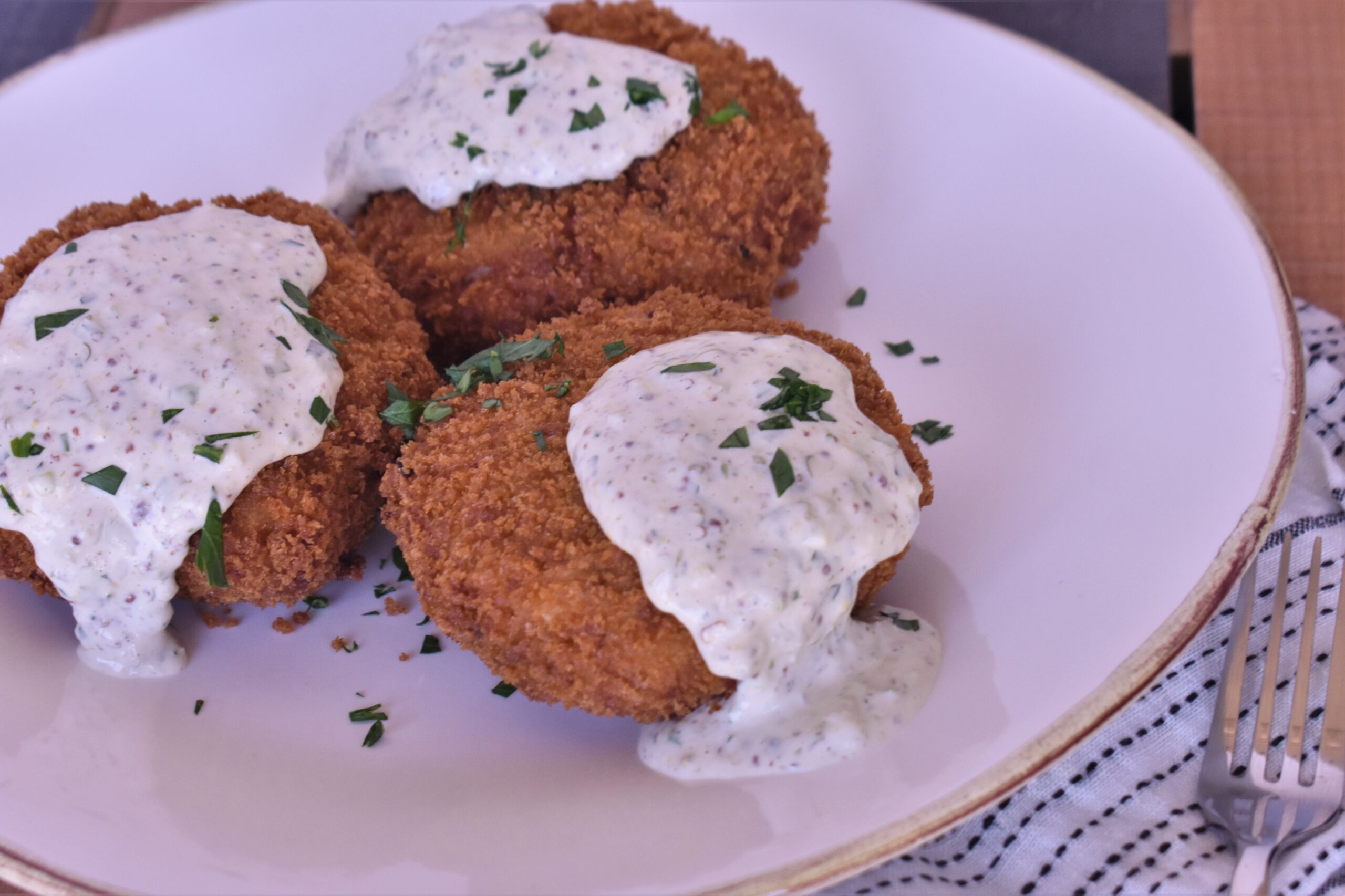 3 pieces of creole crab magic cakes topped with tartar sauce and green onions