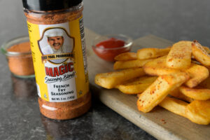 a handful of french fries seasoned with magic french fry seasoning next to a container of french fry seasoning