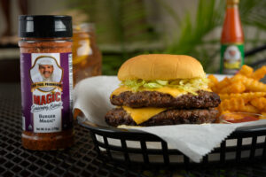 a burger and seasoned fries in a basket next to a container of burger magic