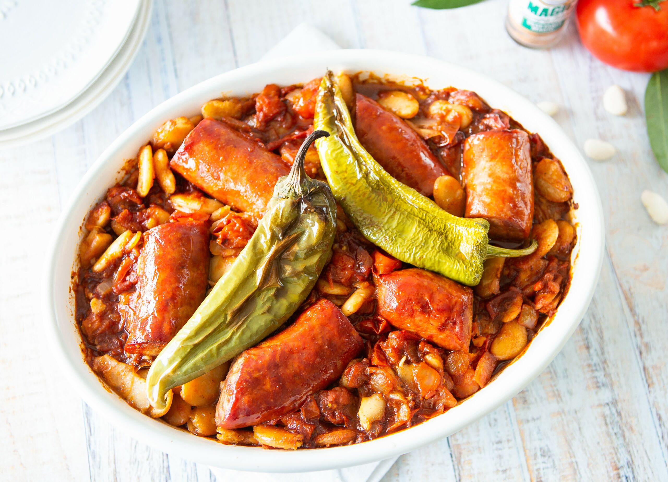 a bowl of macedonian baked beans with 2 jalapeno peppers on top
