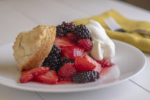 a close up of a piece mixed berry shortcake with a dallop of whipped cream