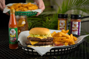 a basket of a burger and season fries surrounded by the burger trio bundle and a sweet tea with a lemon wedge