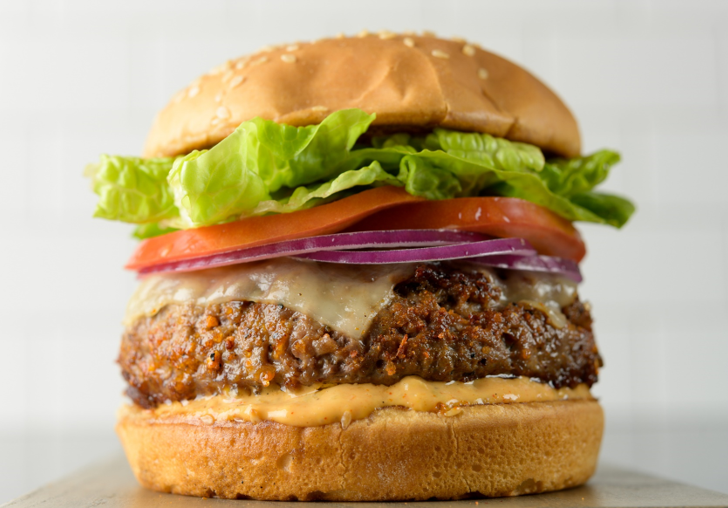 a close up of a fully dressed burger