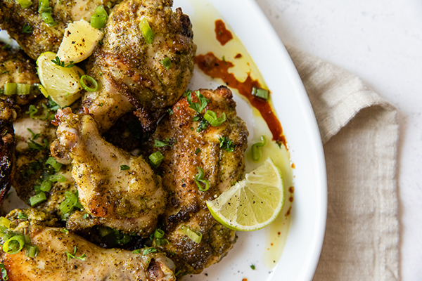 a close up of a plate of grilled jerk chicken with lime slices for garnish