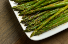 a plate of grilled asparagus with seasoning on it