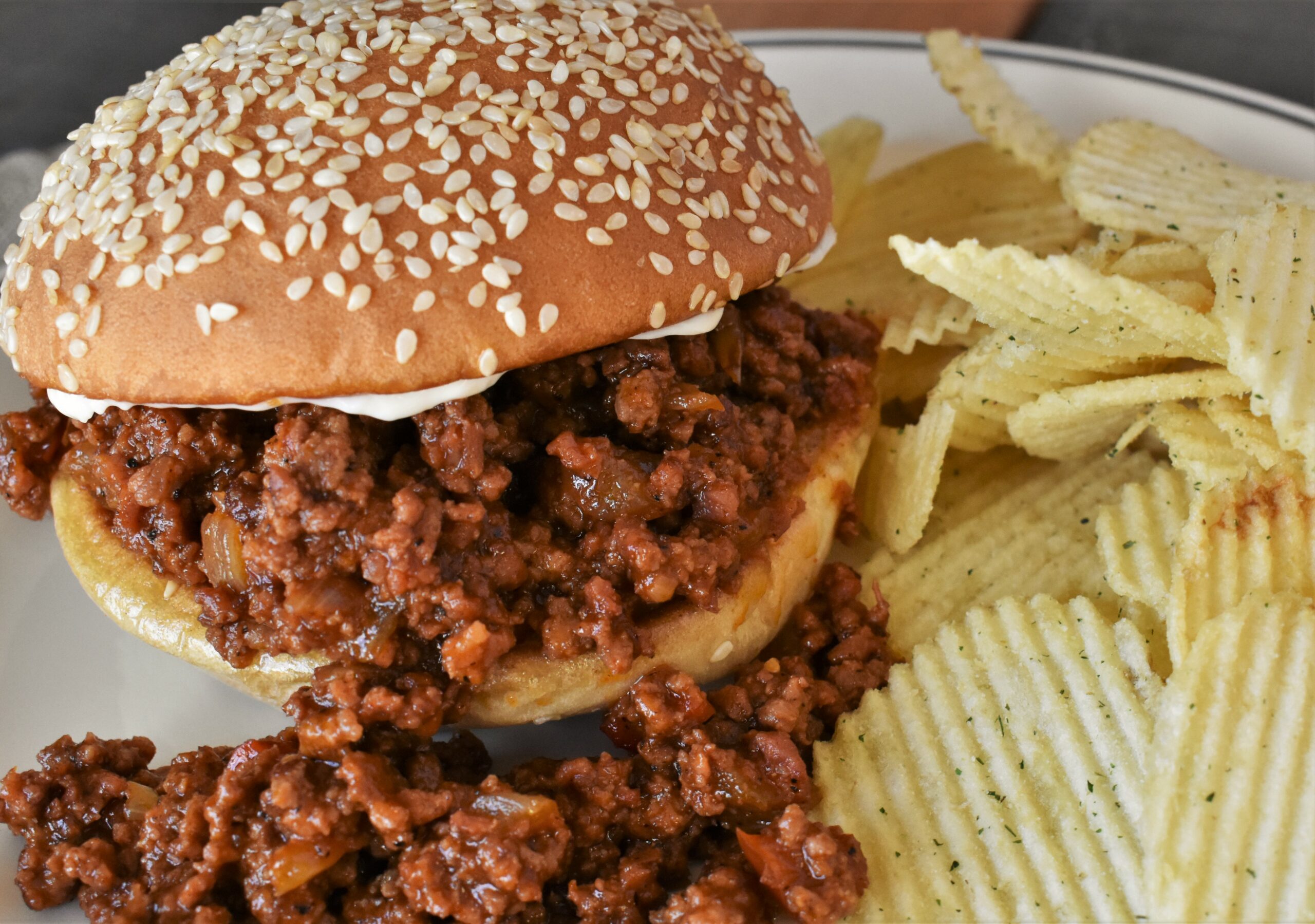 a plate with an andouille sloppy joe and wavy sour cream and onion chips