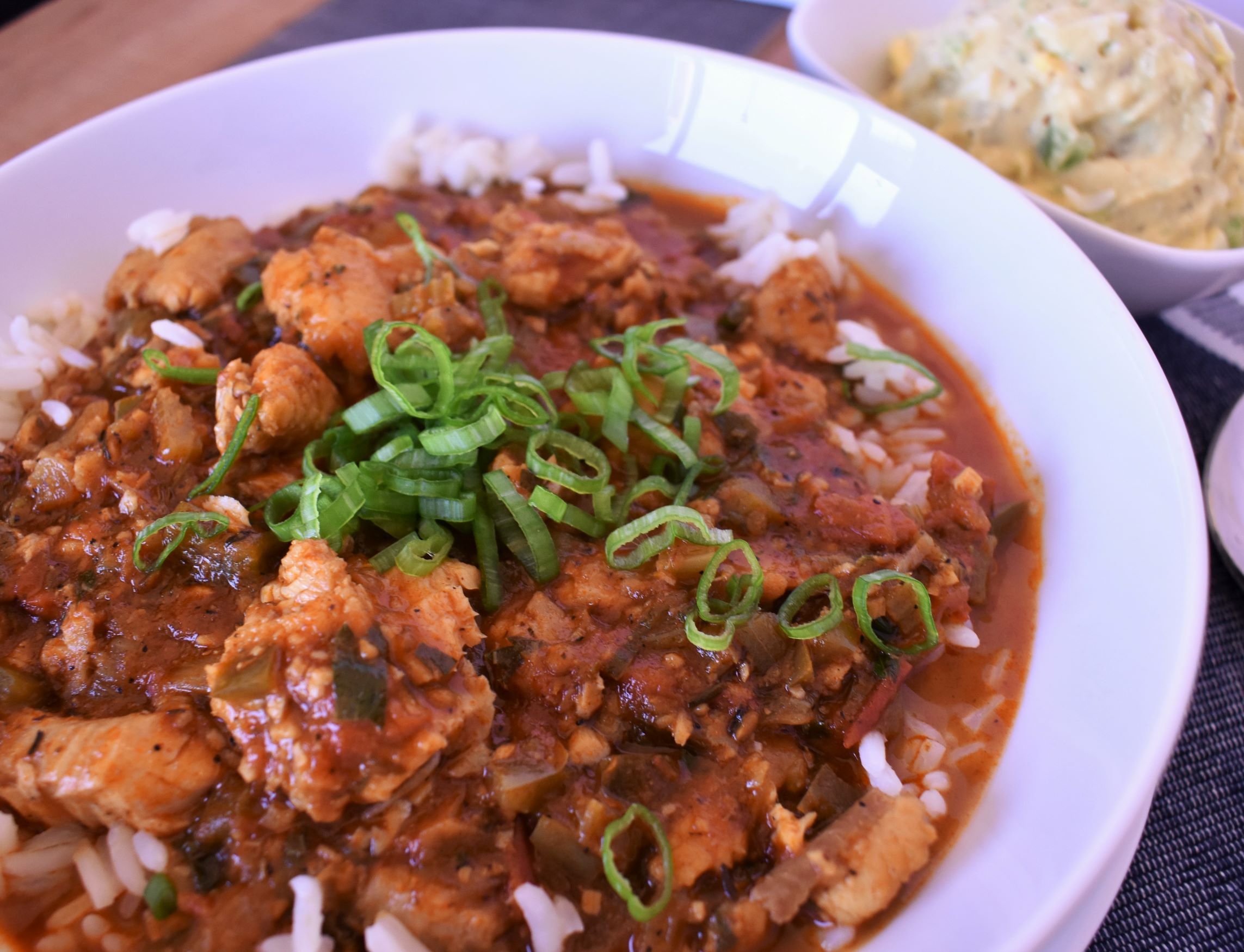 a plate of catfish courtbouillon with a side dish of potato salad