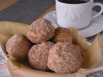 a basket of 6 donut holes next to a cup of coffee