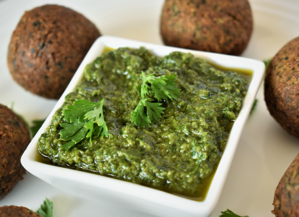 a close up of a dipping cup surrounded by falafels